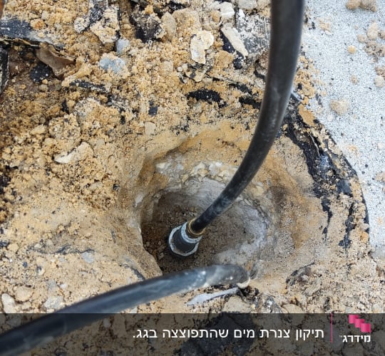 צינור שחור מחובר לחור באדמה עם חול